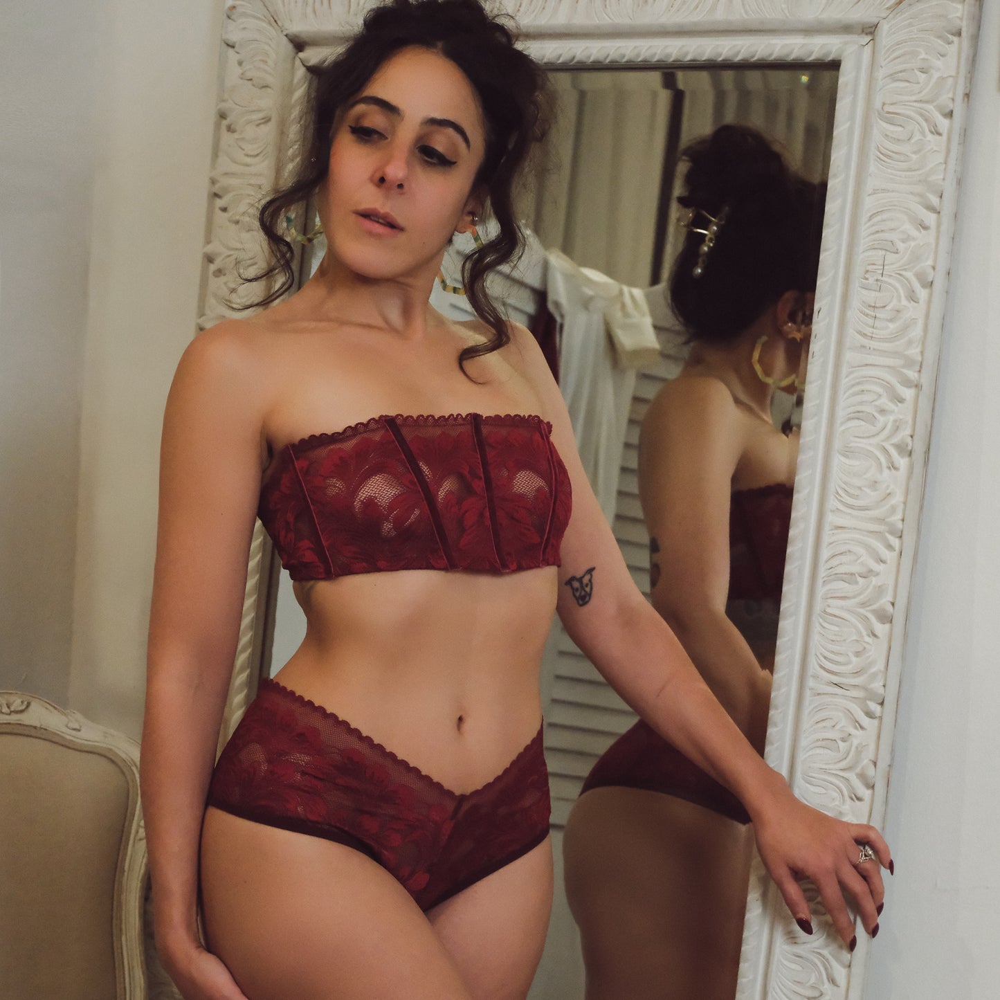 Woman wearing a red lingerie set in front of a mirror.
