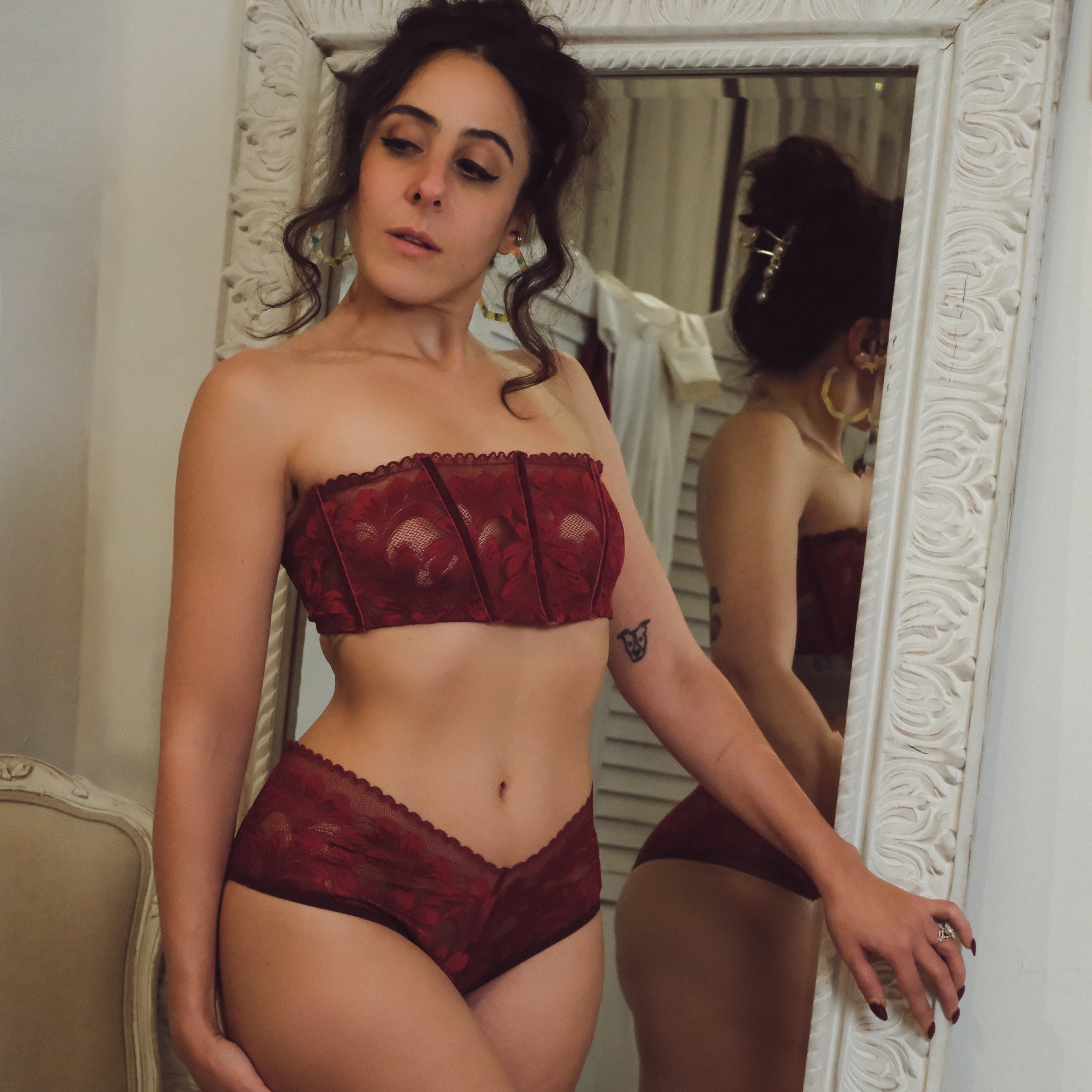 Woman wearing a red lingerie set in front of a mirror.