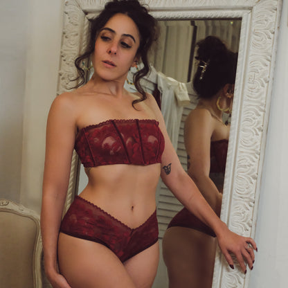 Woman wearing a red lingerie set in front of a mirror.