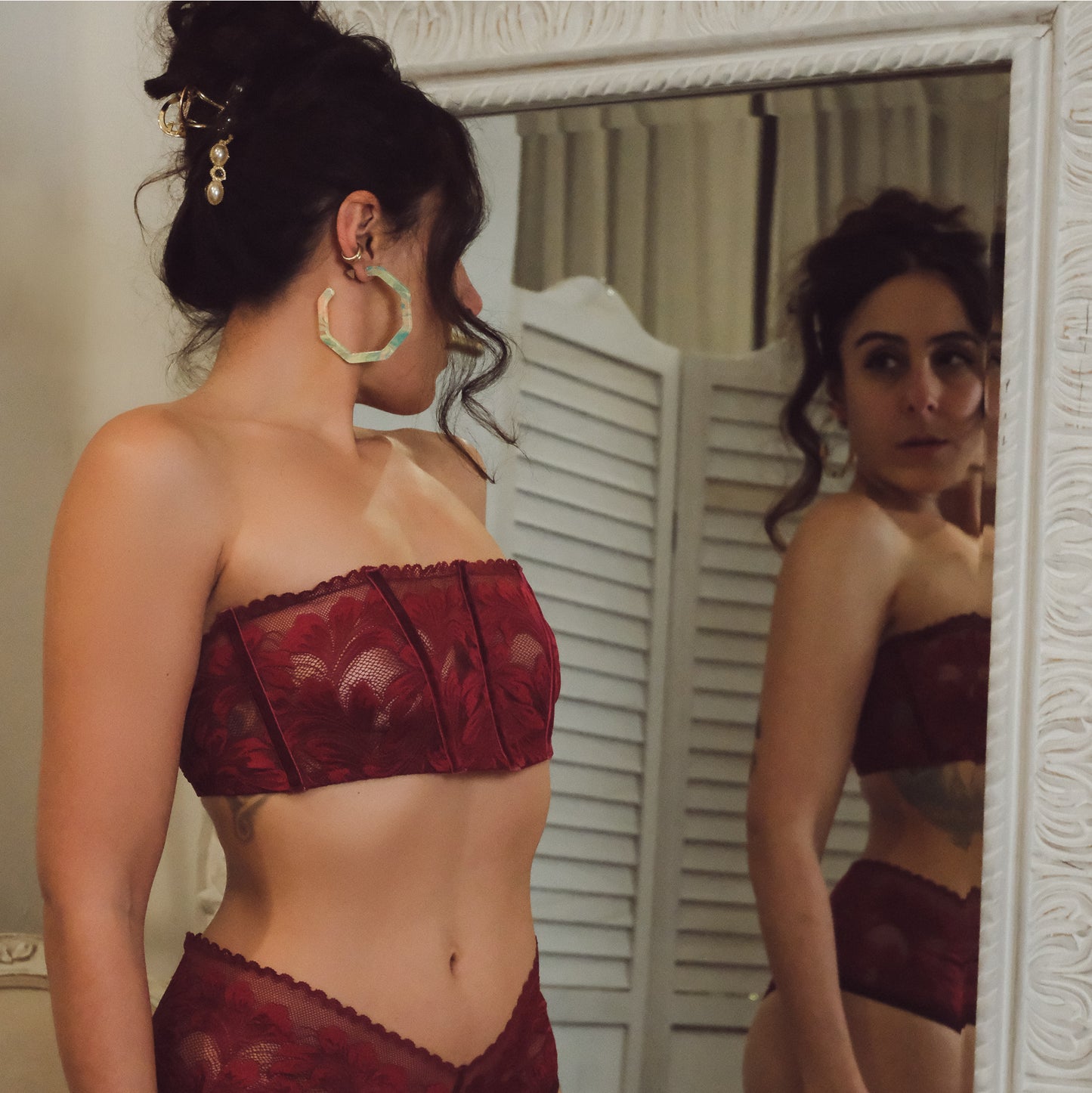 Woman wearing a red lace lingerie set in front of a mirror.