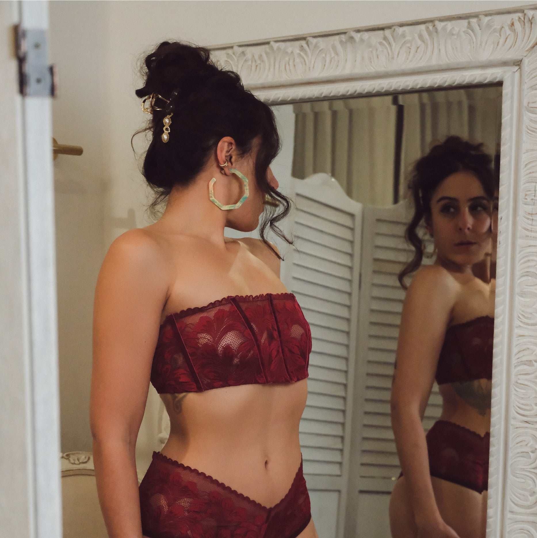 Woman wearing a red lace lingerie set in front of a mirror.